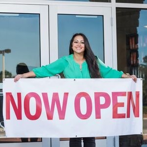 Woman holding a now open sign