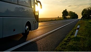 Bus driving on sunset road